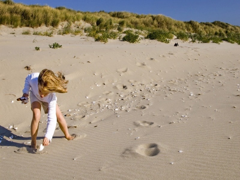 Een kind speelt in het zand bij het strand dat dicht bij onze kleine camping rondom Renesse ligt.